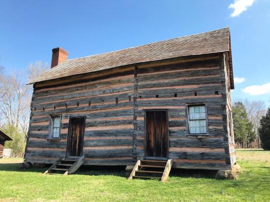 An image of a reconstructed log cabin at the James K. Polk State Historic Site.