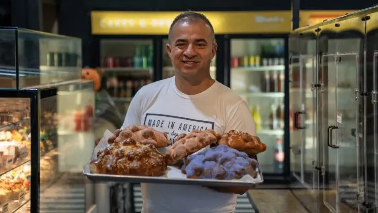 A photo of Manolo Betancur holding pastries and breads.