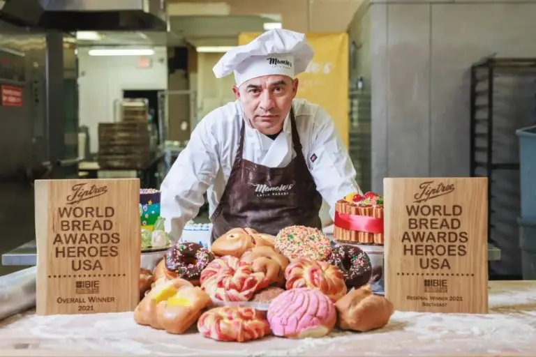 A photo of Manolo Betancur posing with pastries and breads as the World Bread Hero.